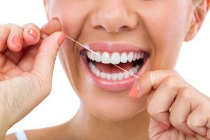 Die Zahnseide muss vorsichtig zwischen den Zähnen eingefädelt werden.